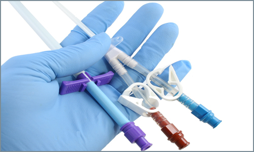 A gloved hand showing three different medical devices made from opaque substrates.