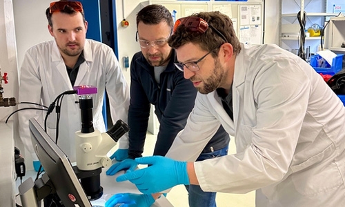 A team of Dymax engineers gathered in a testing laboratory discussing a customer application.